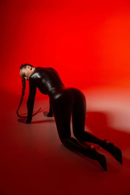 a woman in a black leather suit laying on her side with her feet crossed