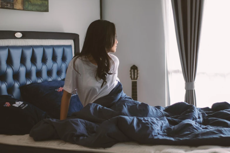 a woman sitting on a bed with a blanket and pillows