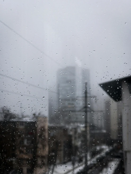 rain falling on a window and buildings in the background