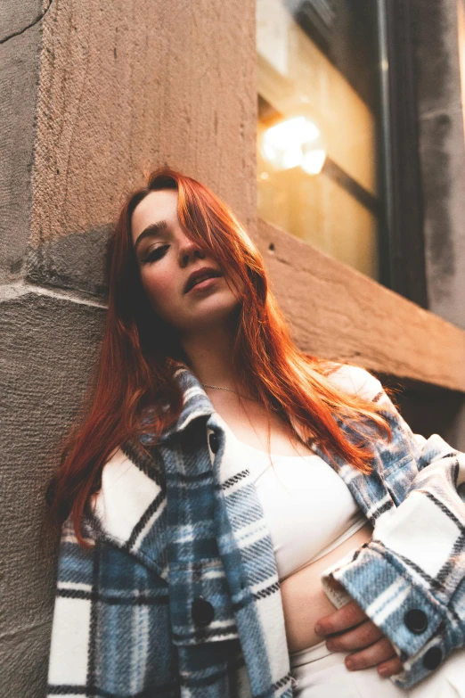 a very tall redhead woman with a plaid shirt standing near a building