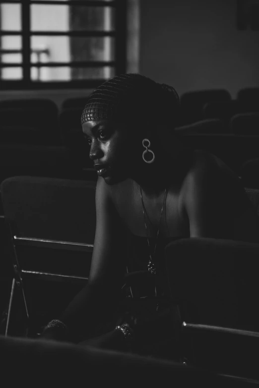 the woman sits alone in the audience while looking into the distance