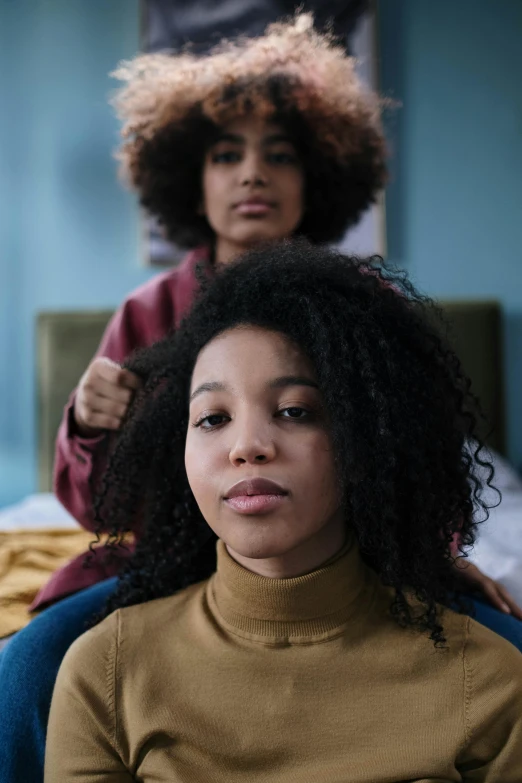 a woman sitting on a bed with her hair dried