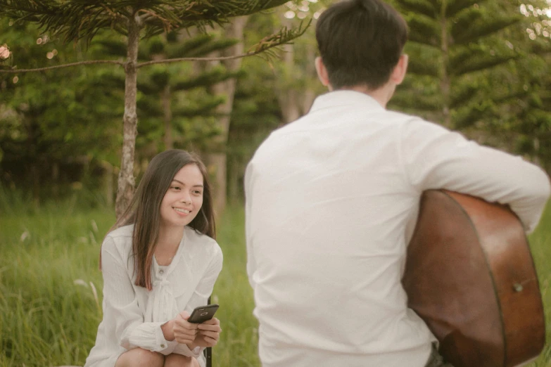 a man sitting down talking to a girl while holding an electronic device