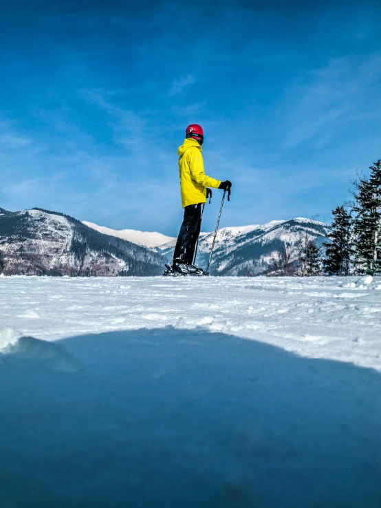 person in yellow jacket holding skis while standing in snow