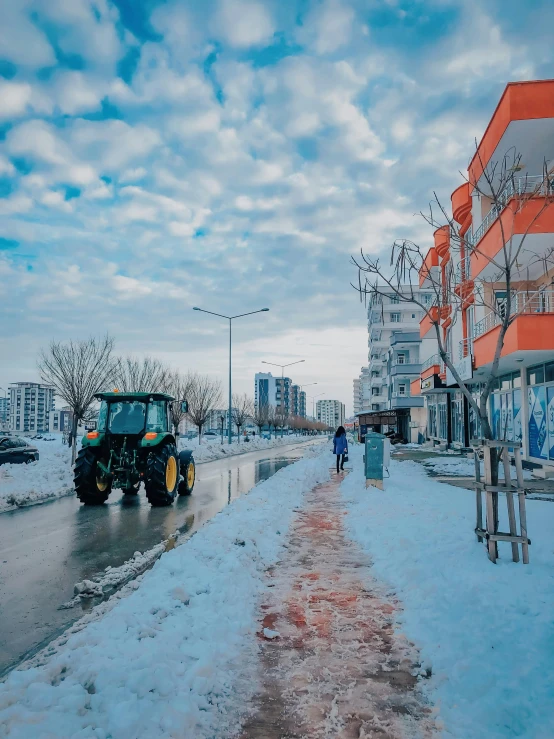 a tractor driving down a snow covered street