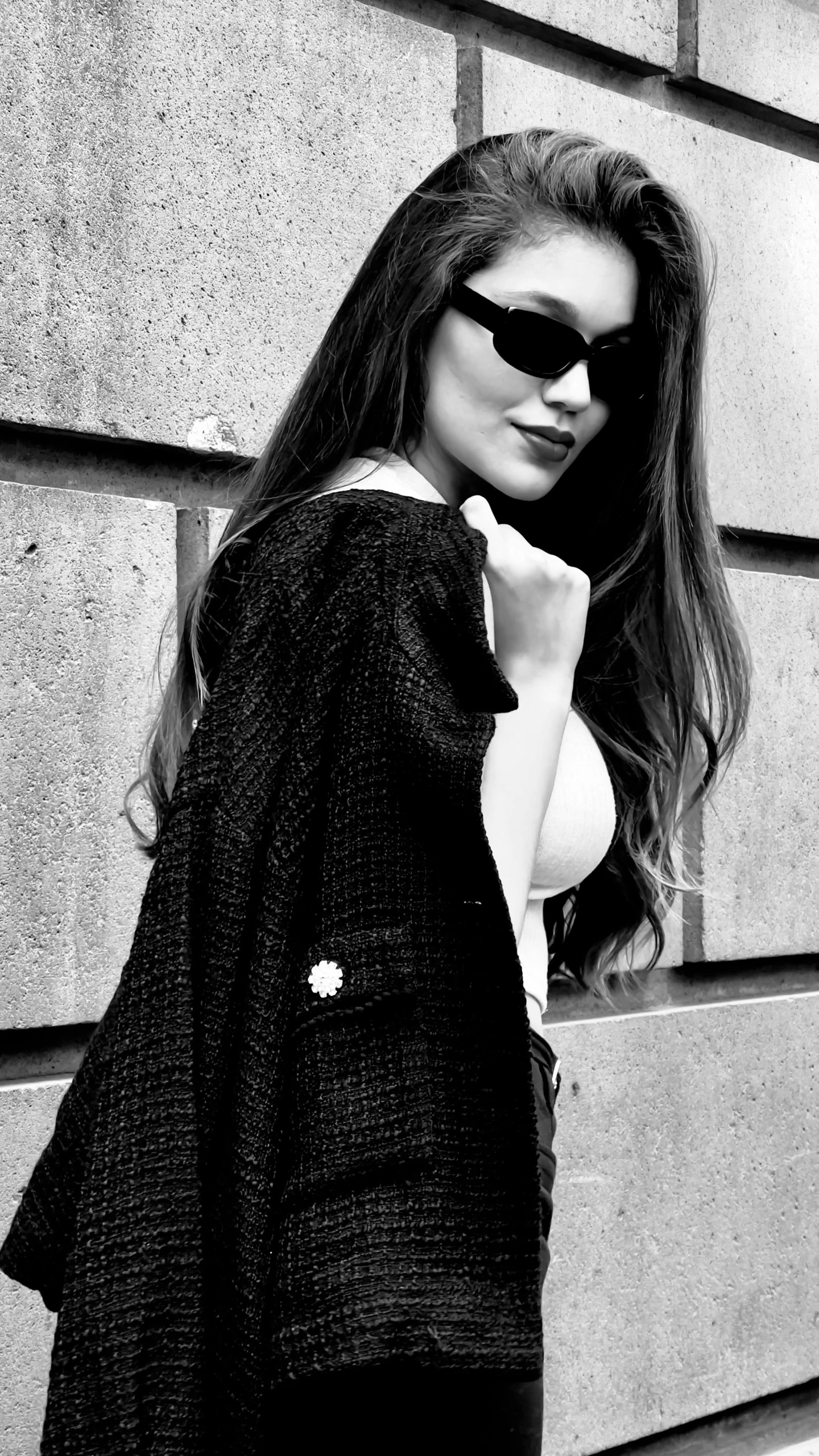 a woman in sunglasses is leaning against a wall