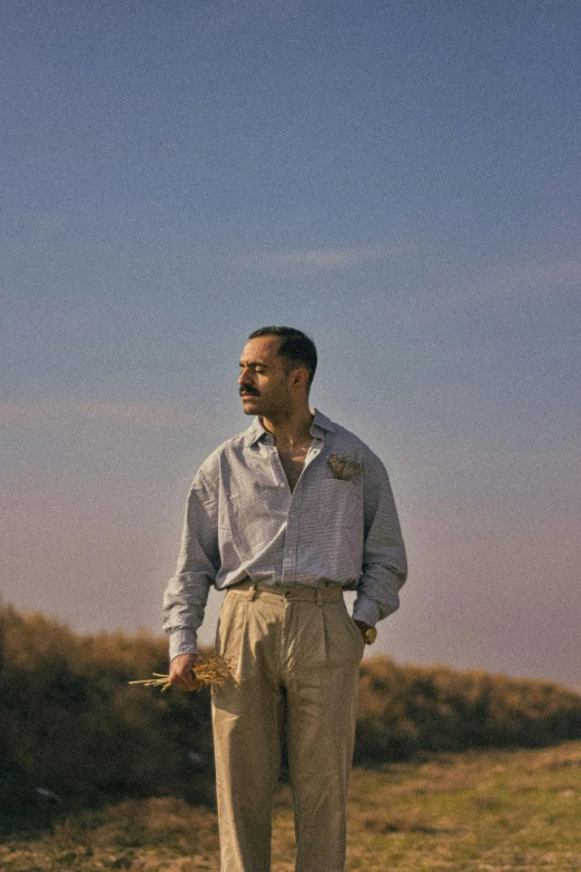 man standing in grass with open mouth and two flowers