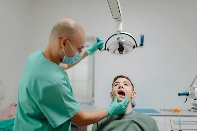 a young man in a dental chair is being held by an instructor