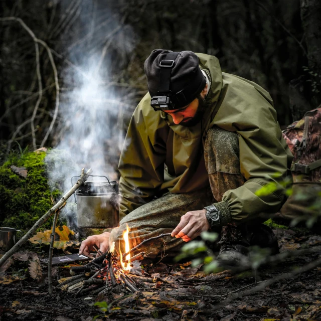 the man is cooking marshmallows on his camping stove