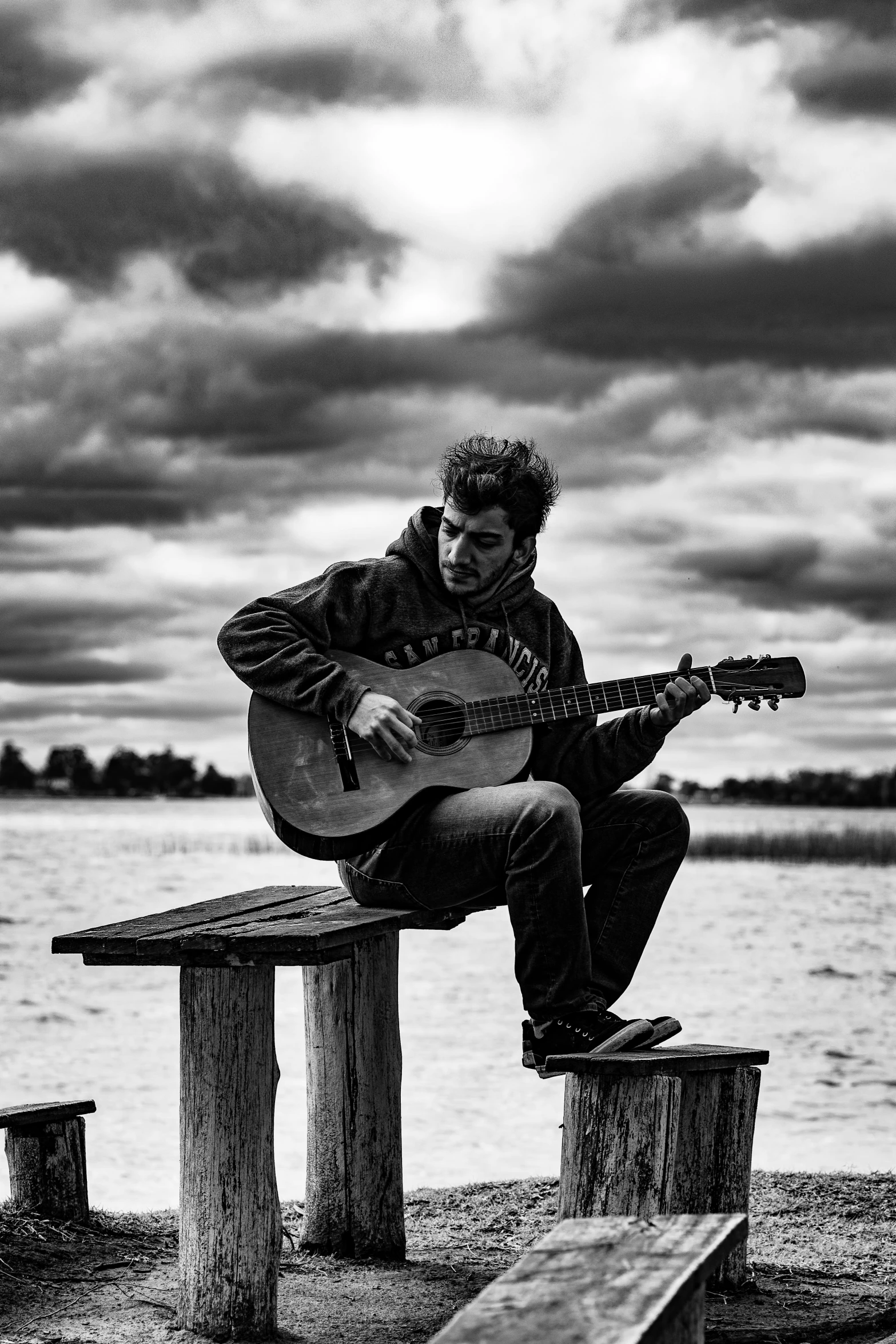 man holding an acoustic guitar on a bench