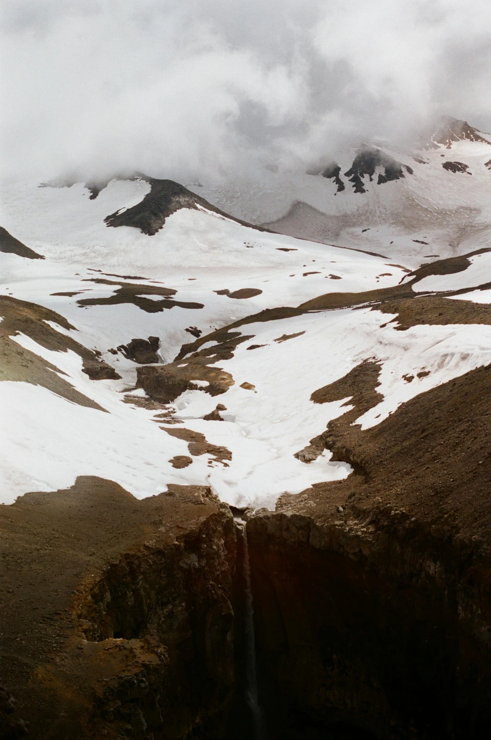 the top of a snow covered mountain on a cloudy day