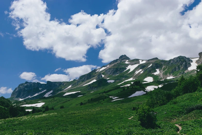 the grassy slopes and rocks have snow on them