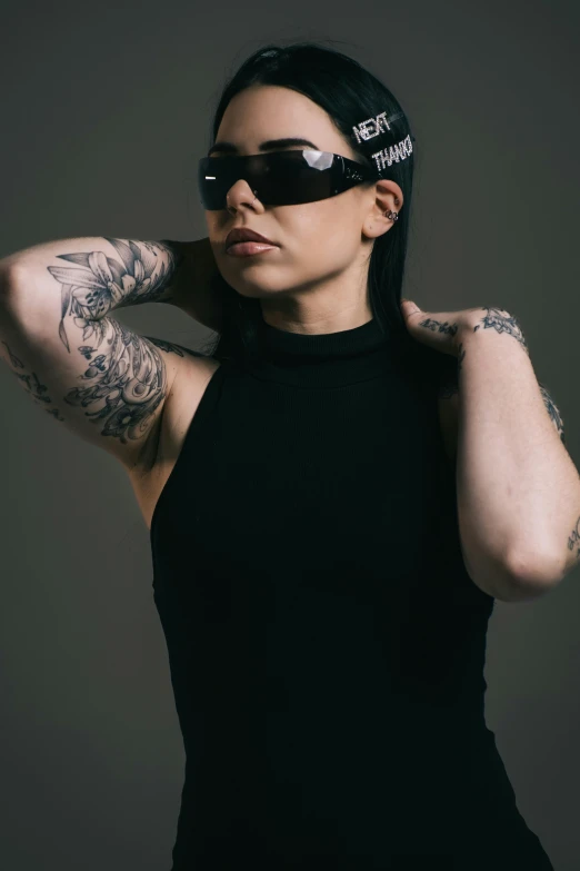 a woman in a black top has some tattoos on her arms