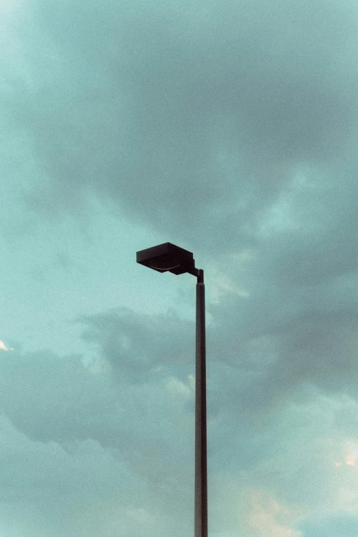 a bright street lamp near the cloudy sky