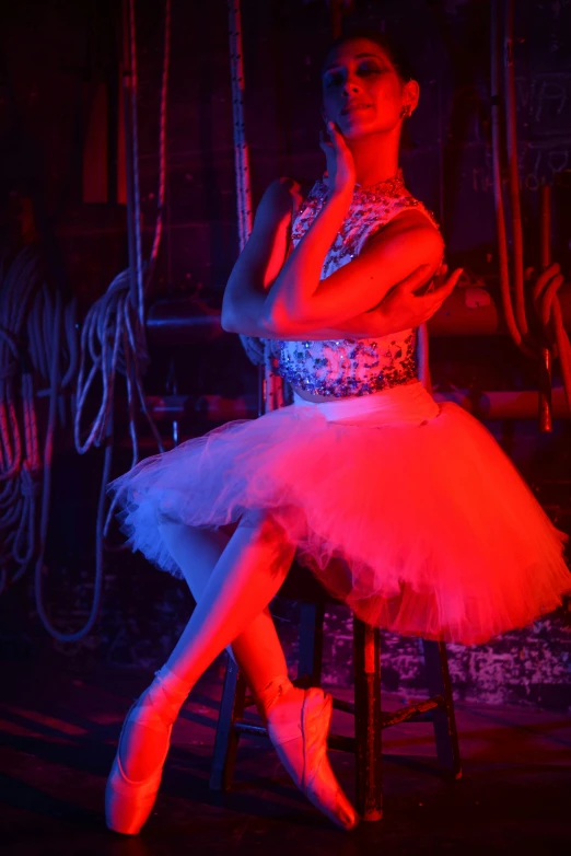 the ballerina is sitting on her chair in a red light