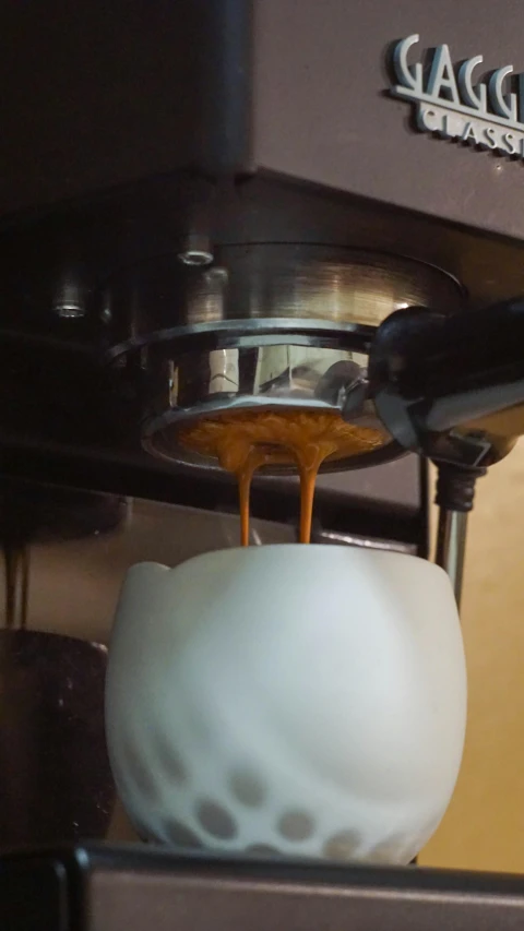 coffee being poured from a coffee maker with a small bowl