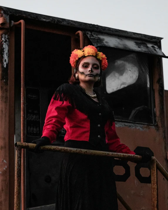 a woman with painted face and long hair wearing a red and black jacket