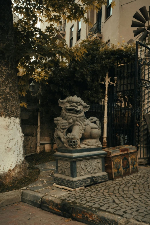 a stone statue of an old man with a hat on is shown near a gate