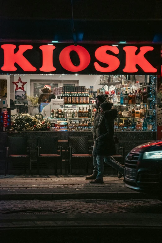 people standing outside of a restaurant with a neon sign