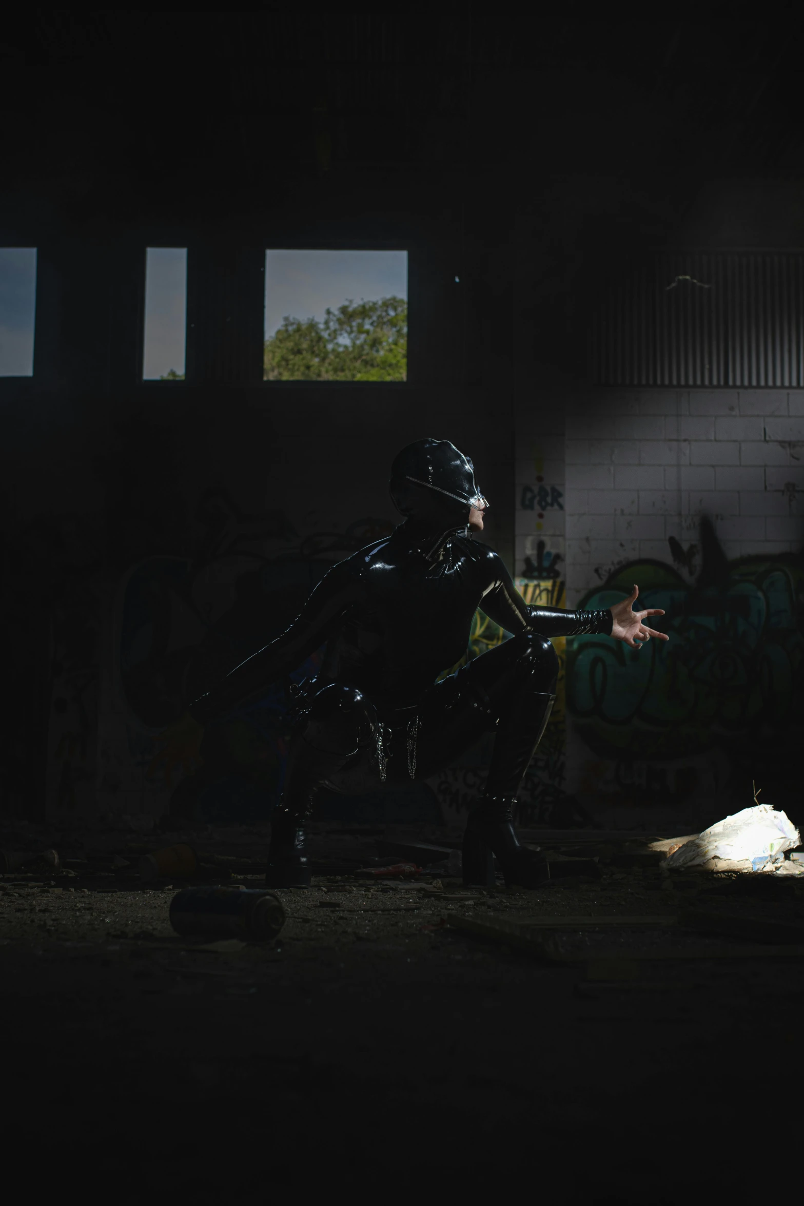 a dark po of a person standing on one foot in an area with lots of grafitti on it