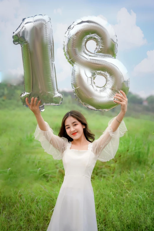 a girl holding up two air balloons, which are shaped like the number six