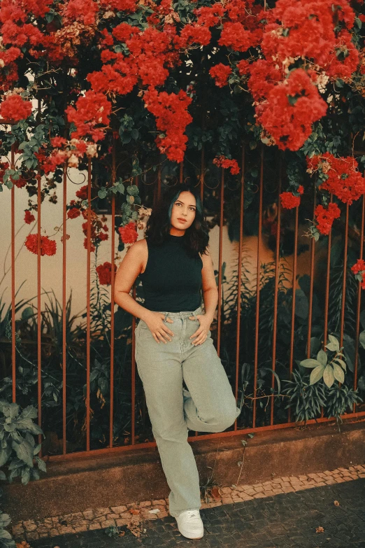 woman standing in front of red flowers, on the street