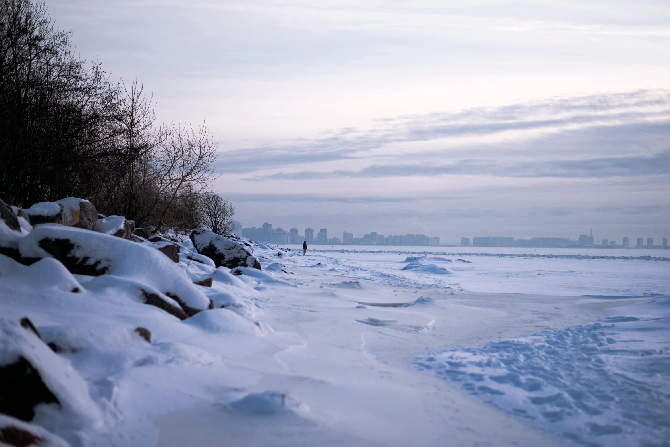 snowy path next to a city on the edge of an icy water beach