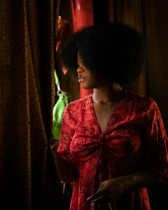 woman in a red dress looking down with large afro hair