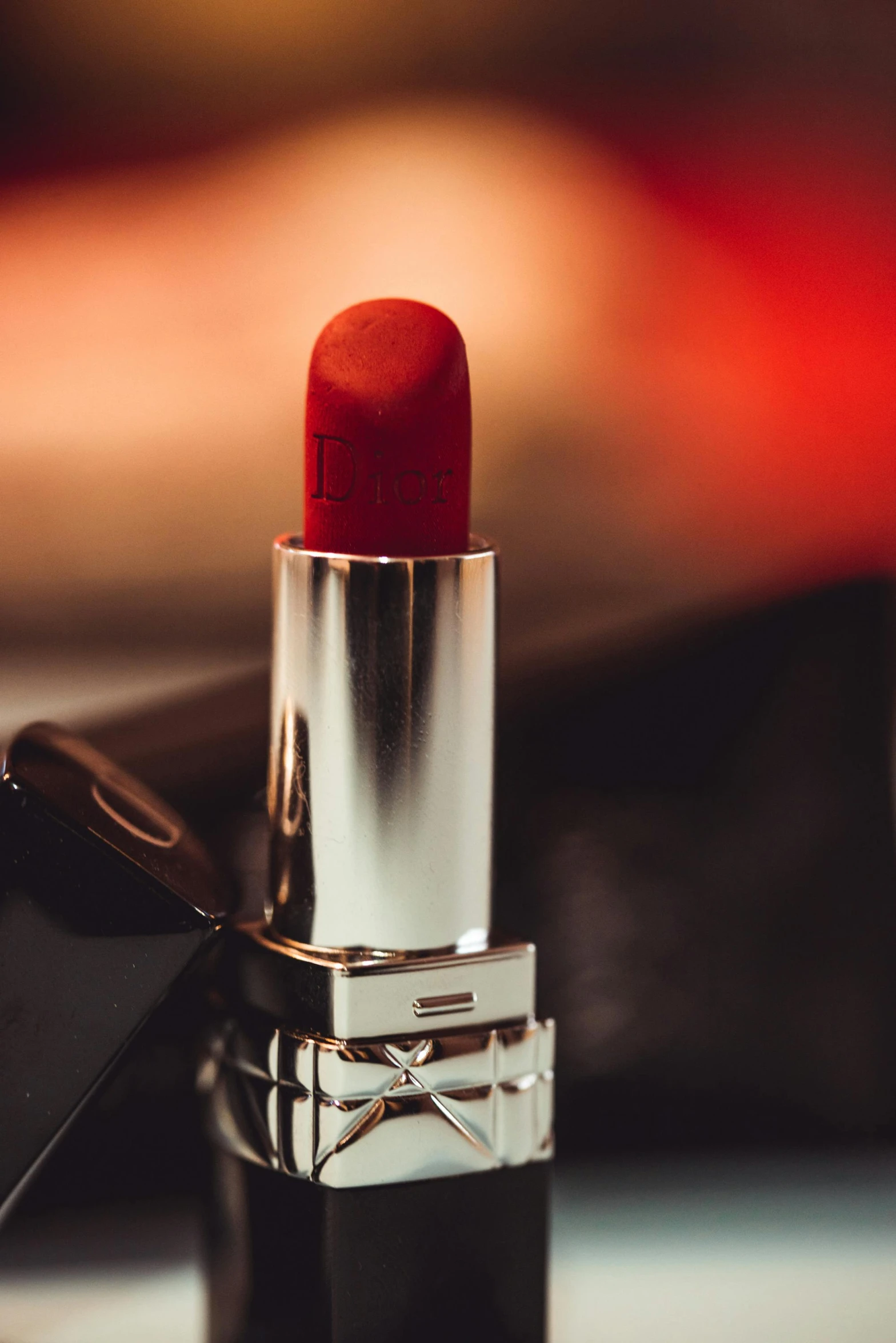 a red lipstick is laying next to a mirror