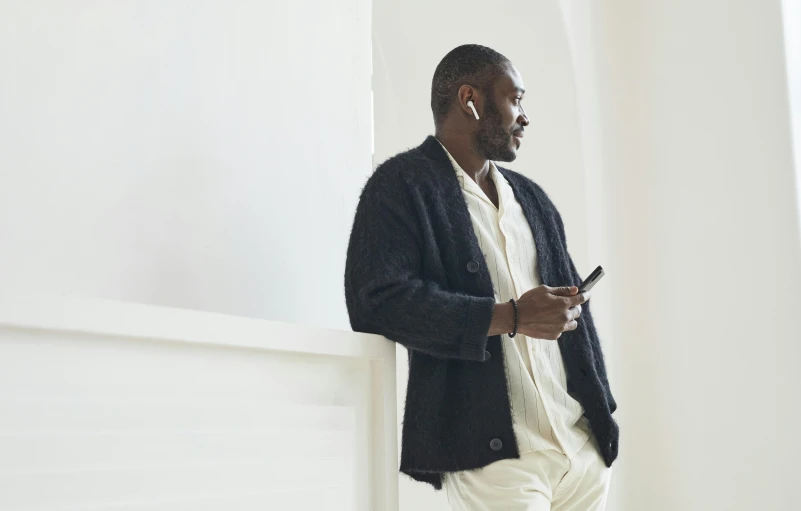 a man in white pants and black jacket standing outside