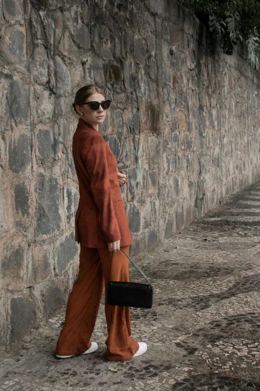 a woman standing on a sidewalk holding a handbag