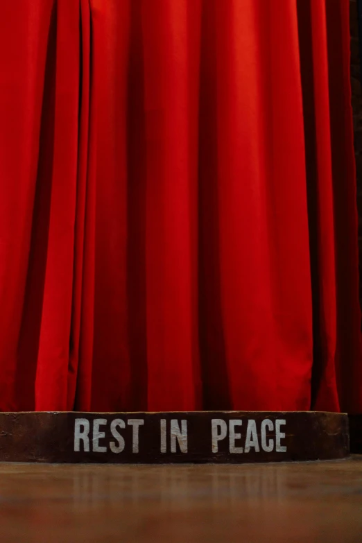 a sign is shown in front of a red curtain