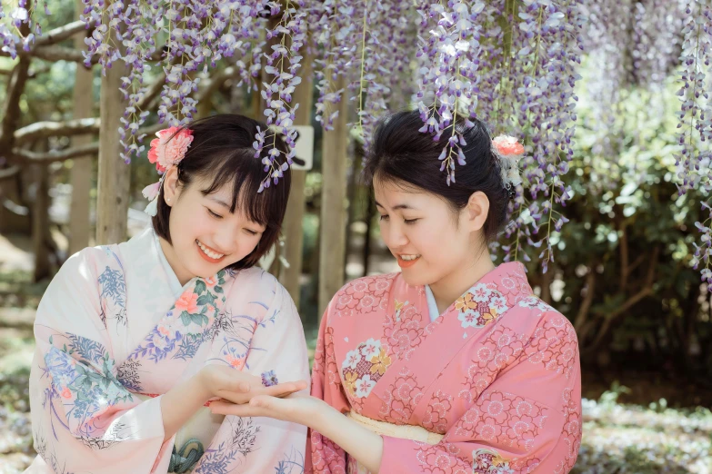 two women in pink robes are standing underneath a tree