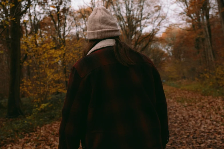 a person wearing a hat standing on a path in the woods