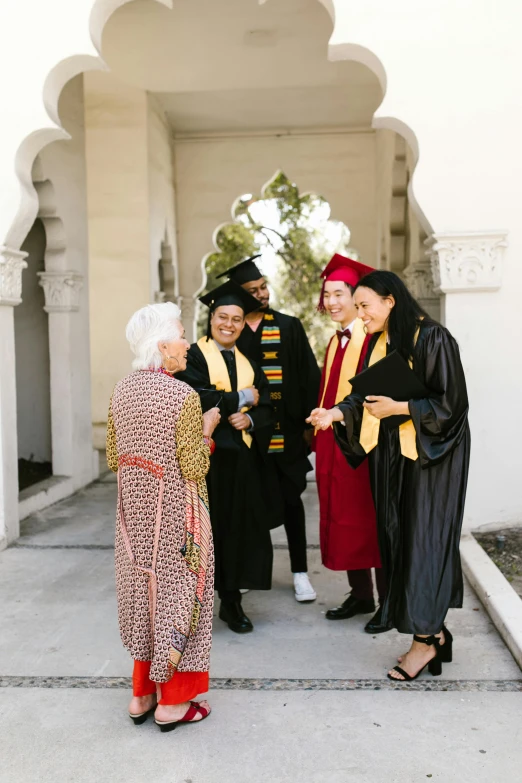 an indian graduate greeting three other graduates