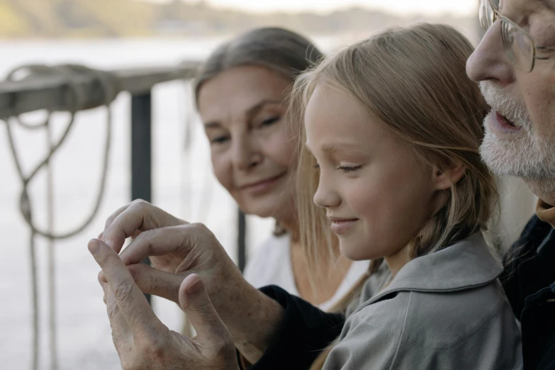 two adults and one child are looking at soing on a phone