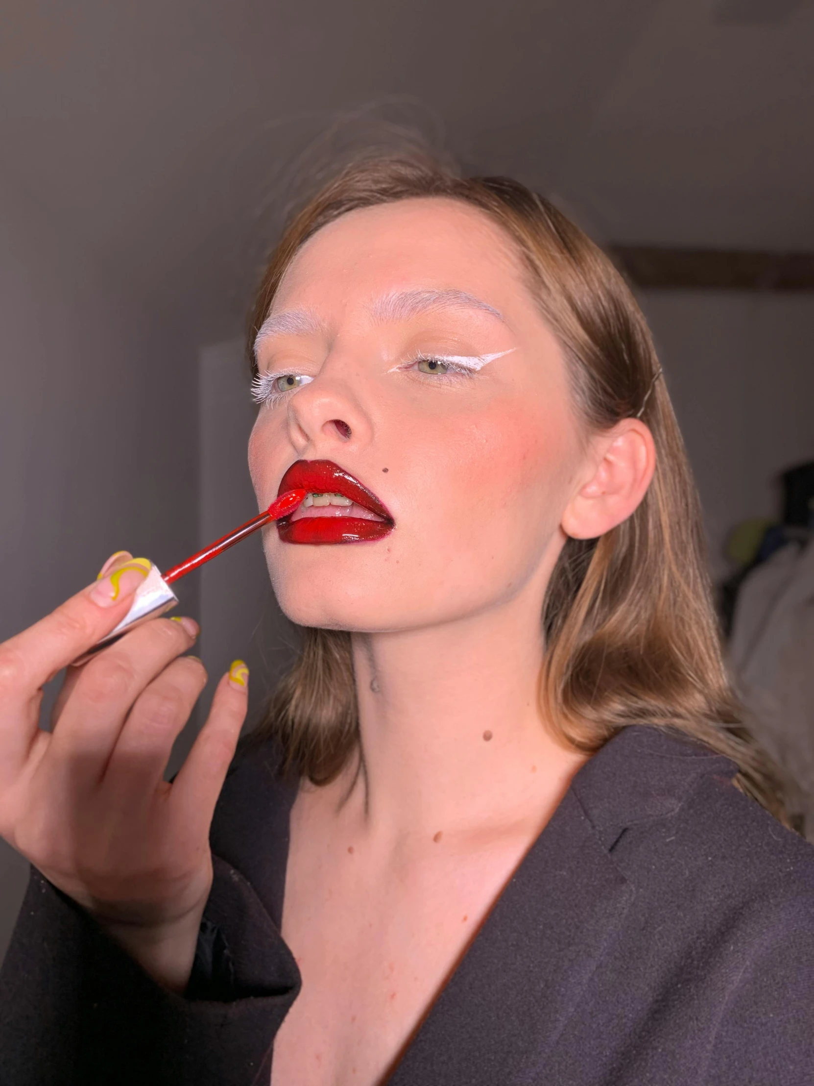 a woman with red lipstick and makeup applying her face