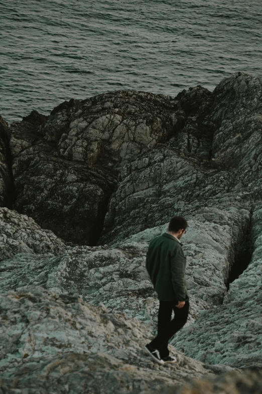 a man in the middle of some rocks by the ocean