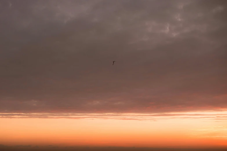 an airplane flying in the sky at sunset