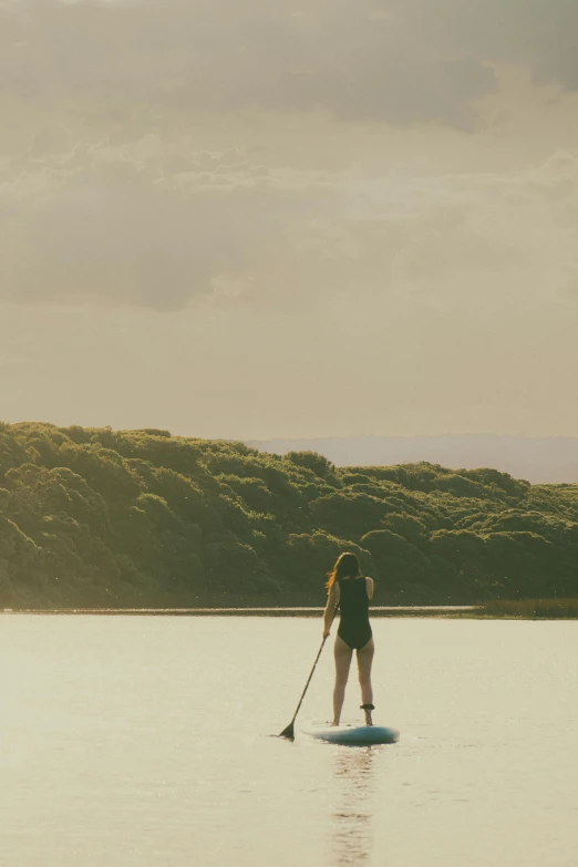 a girl paddle boarding in calm water on a sunny day