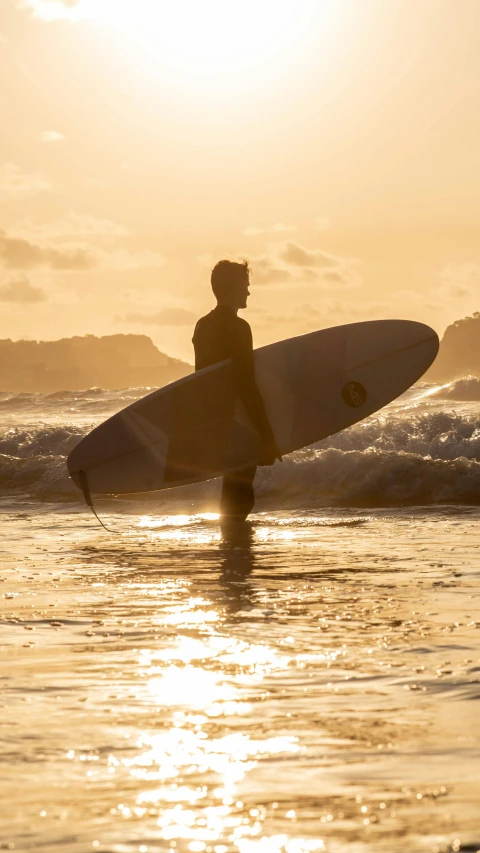 person walking out into the ocean with a surfboard