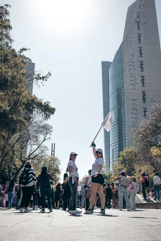 people holding a flag and some onlookers standing in front of tall buildings