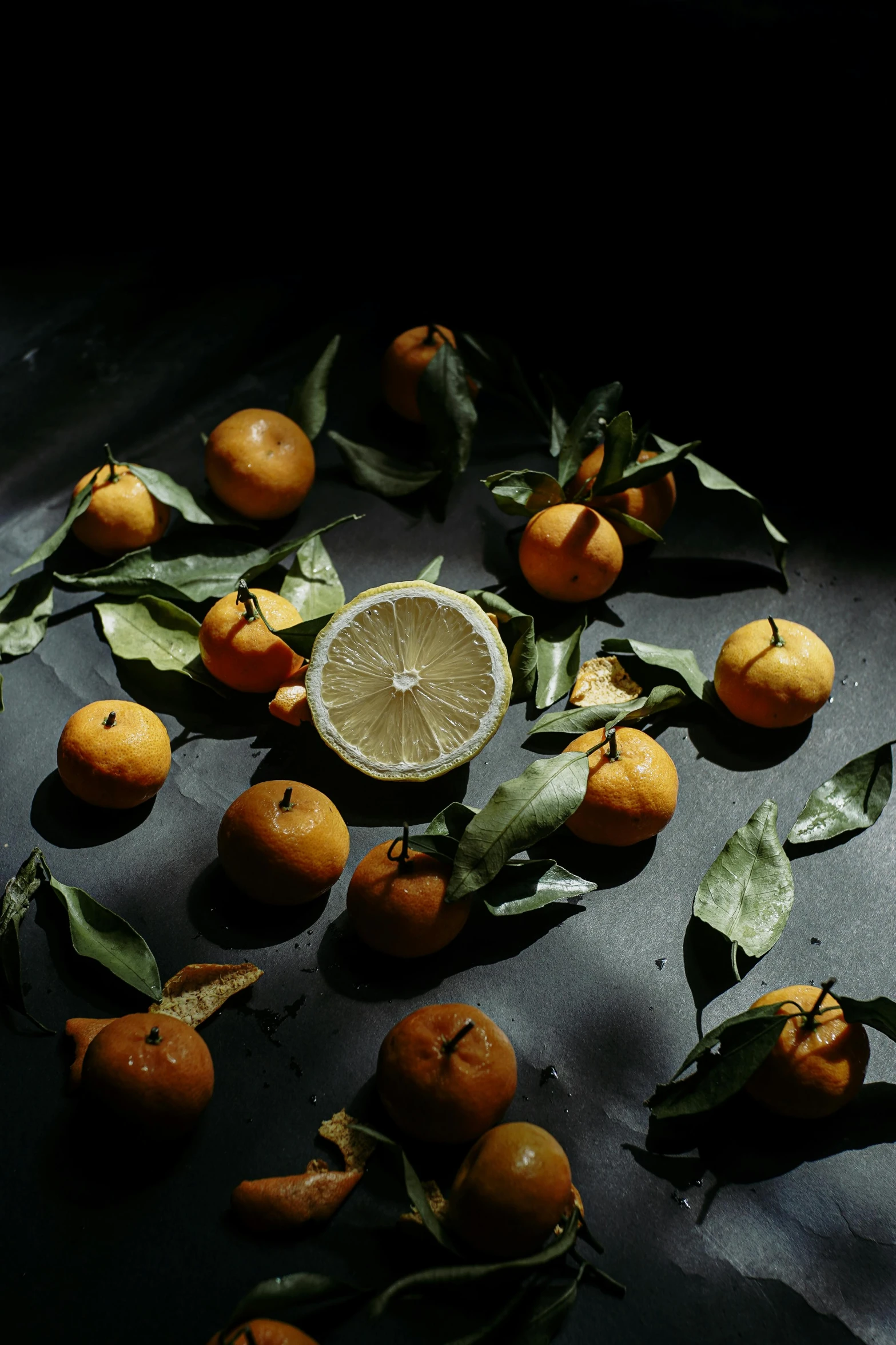 group of small citrus fruits with leaves laying on a table