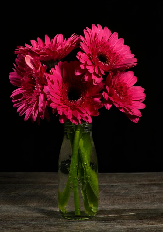 a vase with water, some petals, and some buds