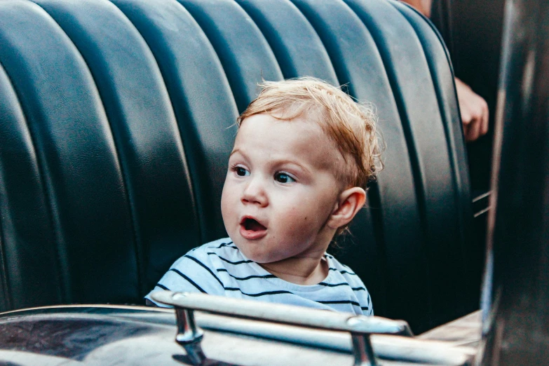 a little  with his mouth wide open sitting in a chair