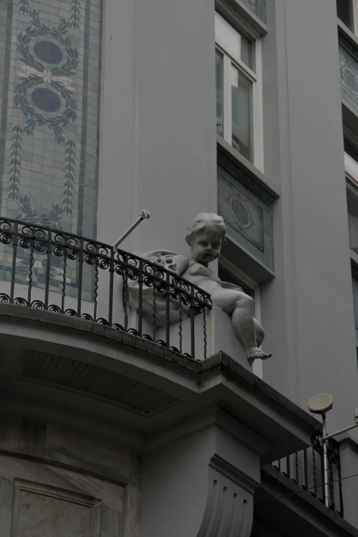 statue on balcony in urban setting with clock on building