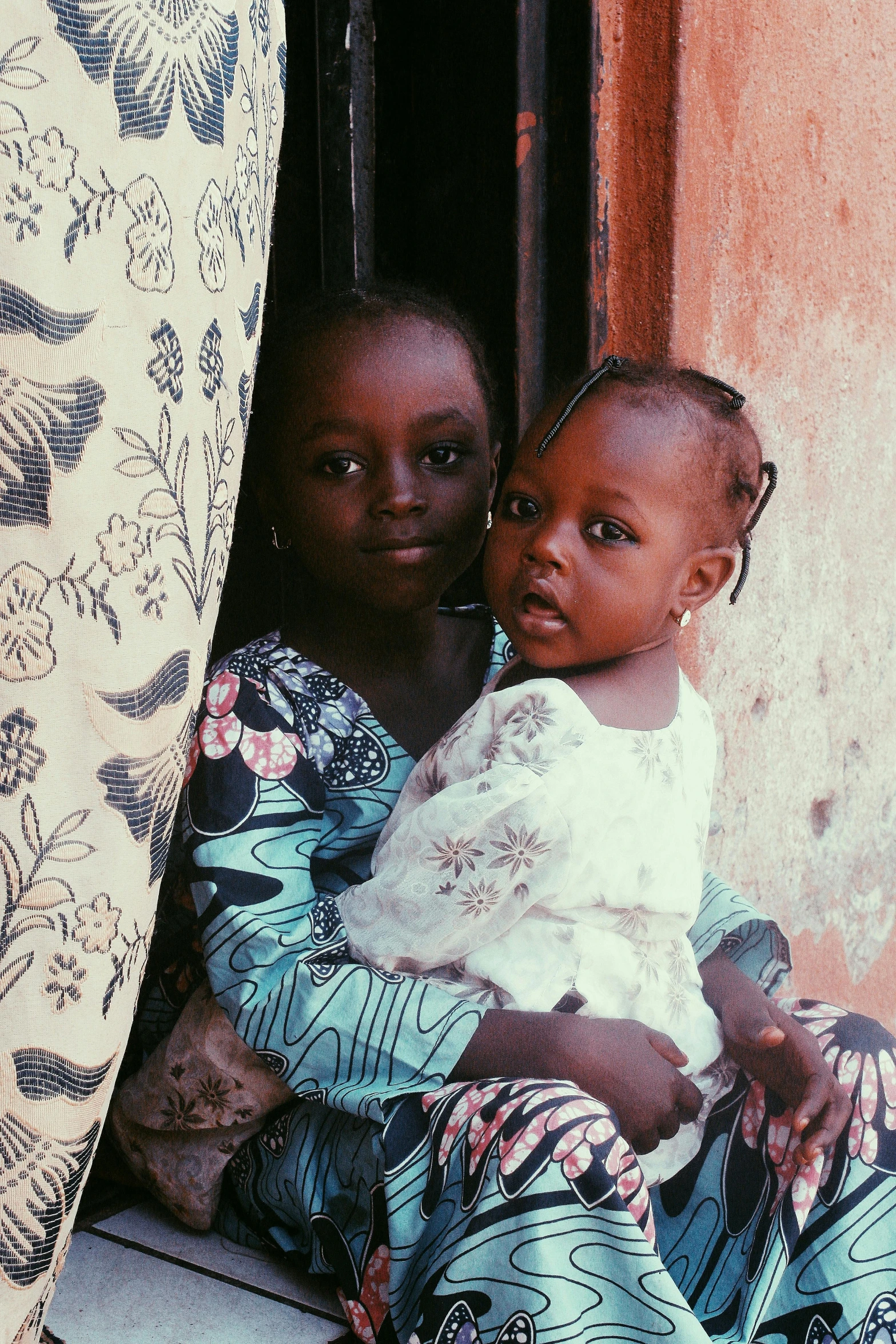 two little girls with one baby sit together