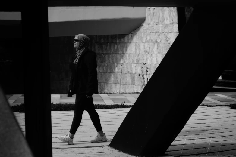 a man in black walks across a wooden walkway
