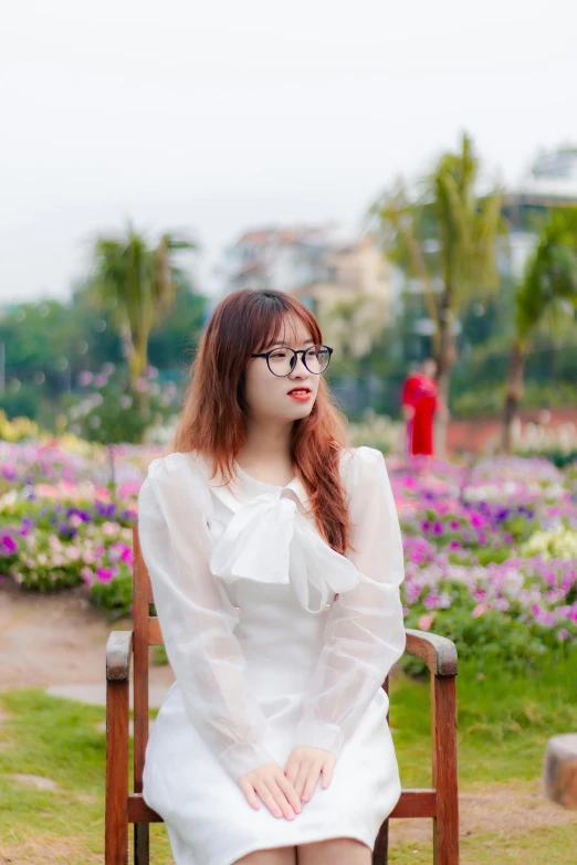 a girl in white shirt and pants sitting on a chair