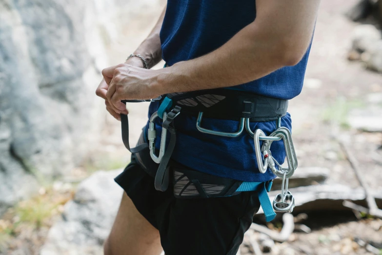 a man wearing climbing gear holds onto some ropes